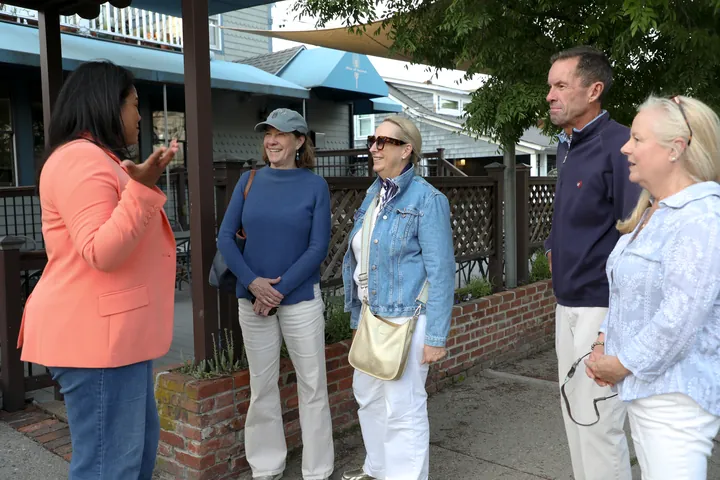 Angela Lima in conversation with four neighbors outside a Newport storefront