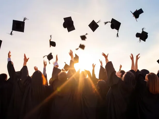 Graduates throwing their caps in the air at sunset